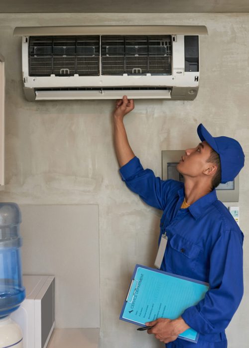 Young Asian technician checking conditioner in kitchen